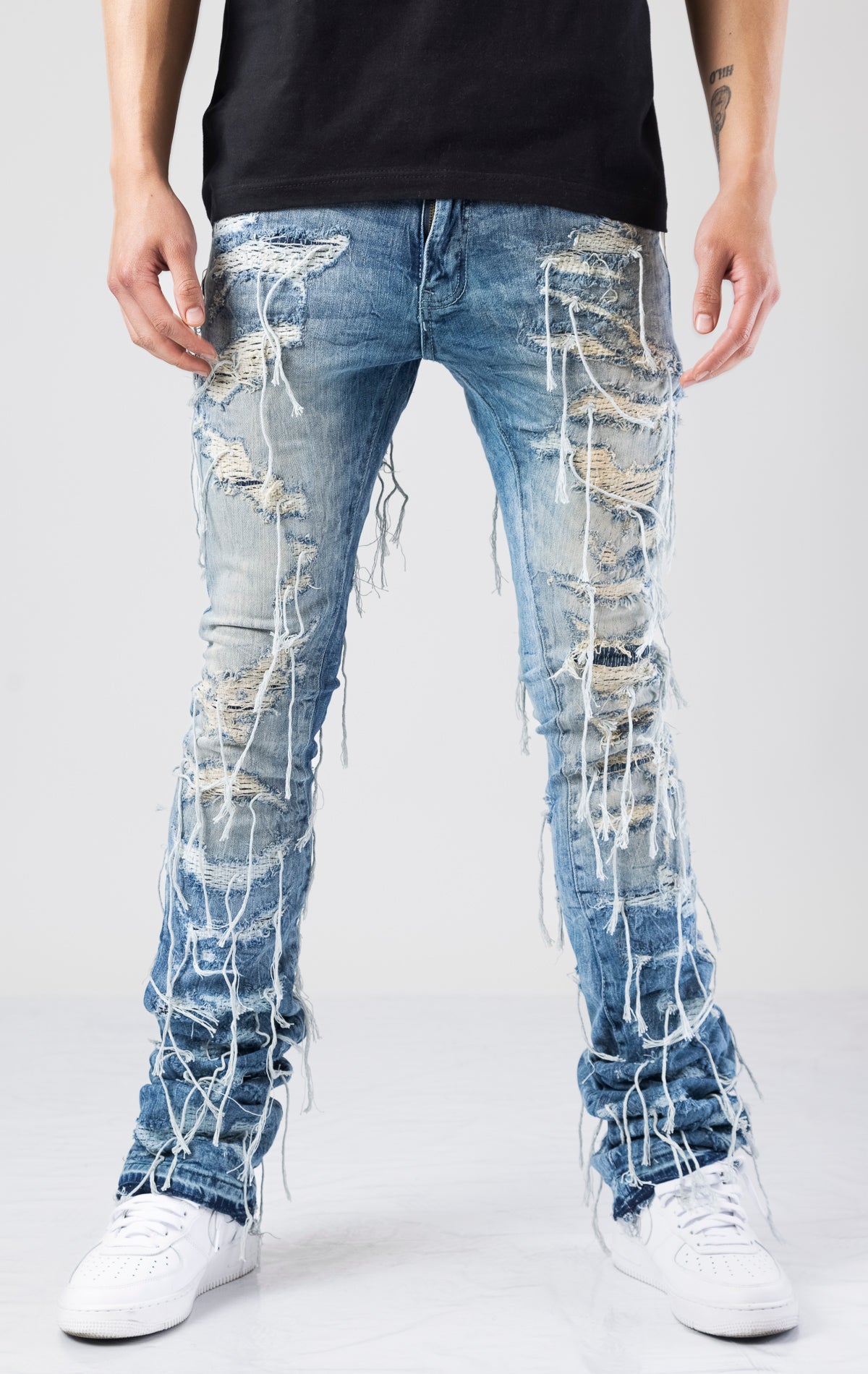 Slim fit jeans with a regular rise and tapered from the knee to the ankle. Features heavy shredding throughout with a hanging weft, rip, and repair design.