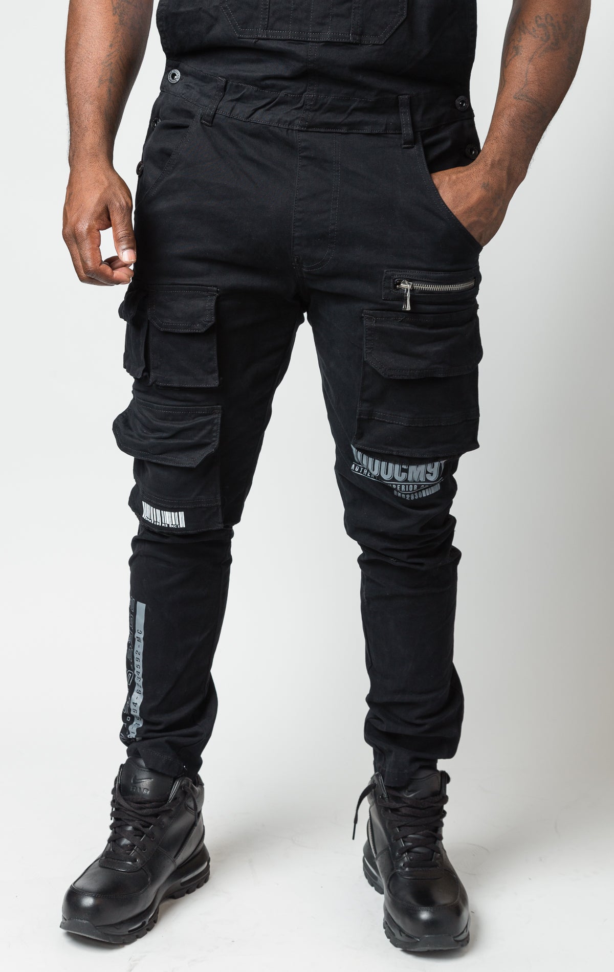 black Cotton twill overalls with cargo pockets and adjustable shoulder straps.