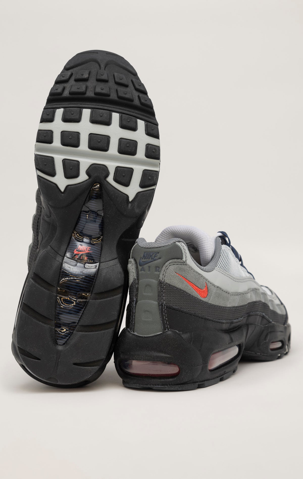 A black Nike Air Max 95 sneaker with a wavy mesh upper and visible Air cushioning units in the heel and forefoot. Anthracite and smoke grey accents contrast with pops of track red for a bold look.