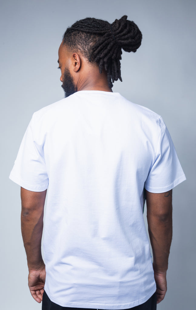 Back side of white shirt with short sleeves and a ribbed crewneck collar. World Tour Tee features dynamic visuals and a stitched Lucky Charm logo