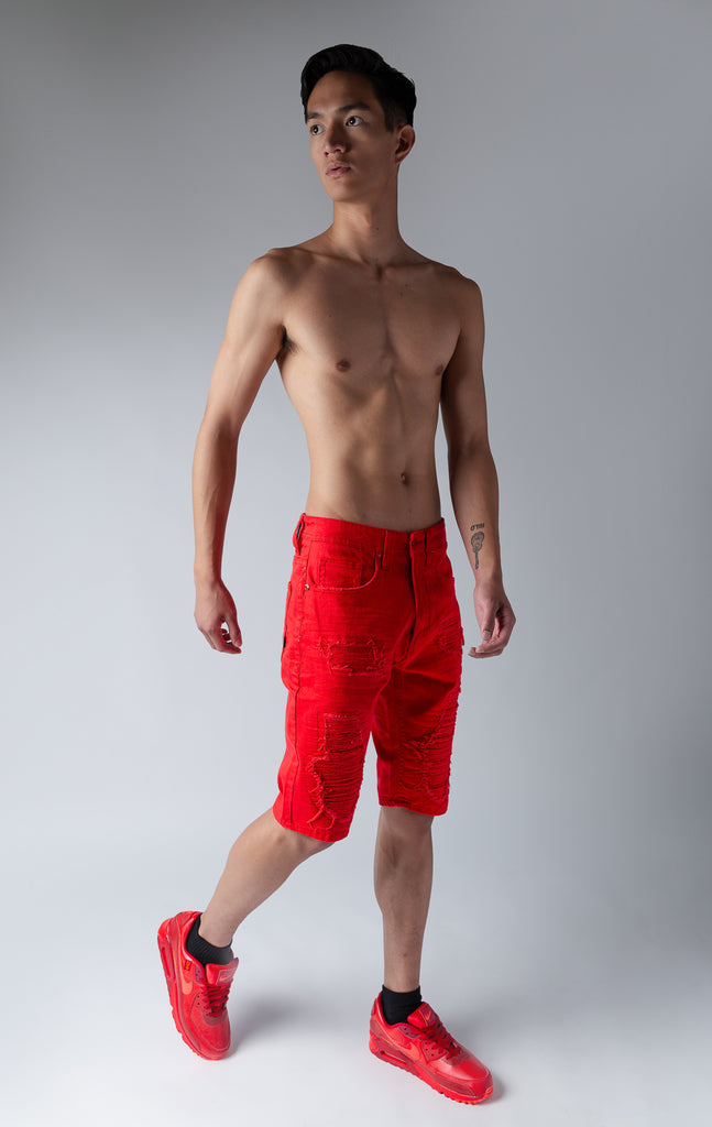 Model wearing red denim shredded shorts with fused shreds, crinkle effect through out
