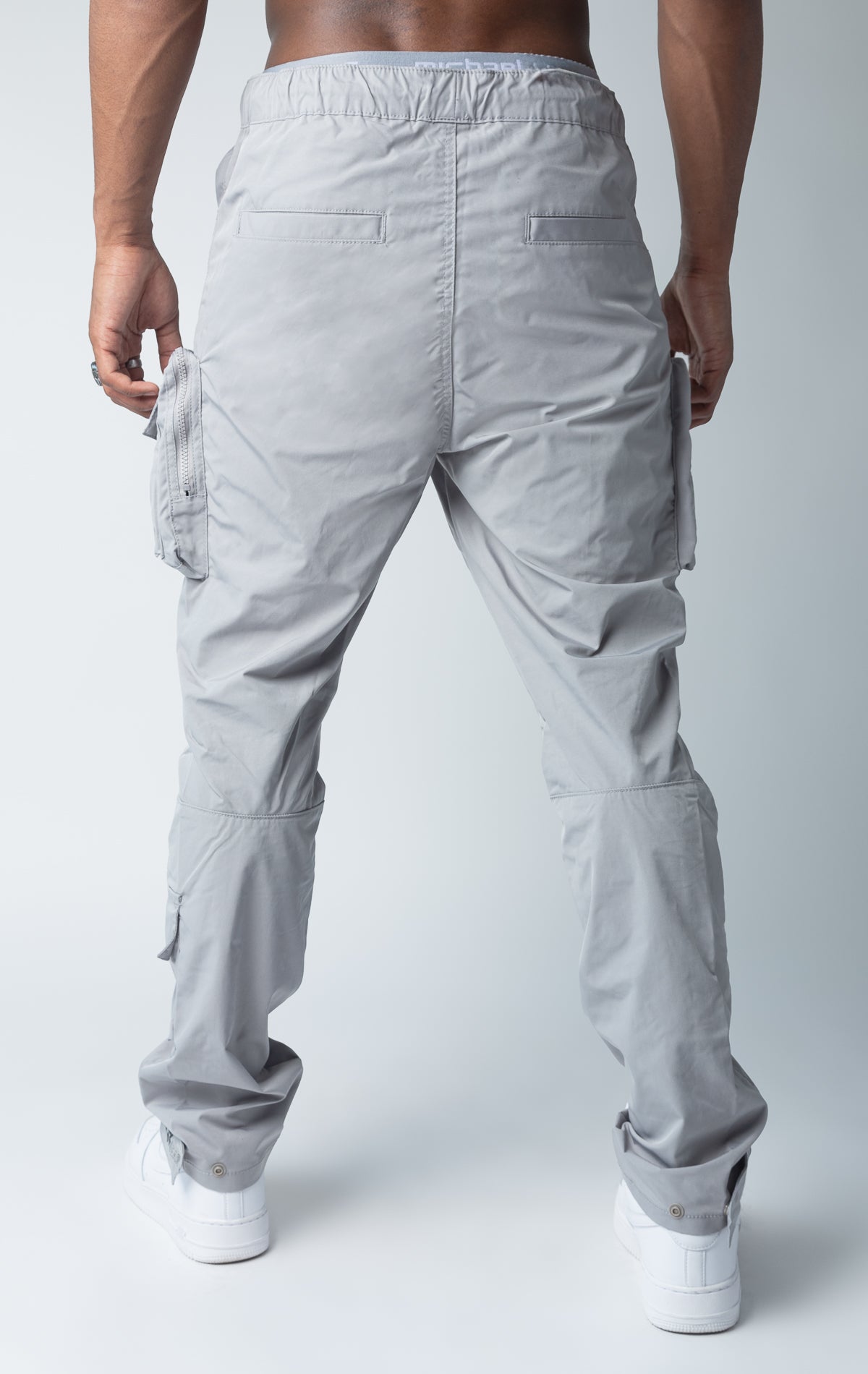 Grey windbreaker utility pants, sleek fit with an open bottom jogger style, back side
