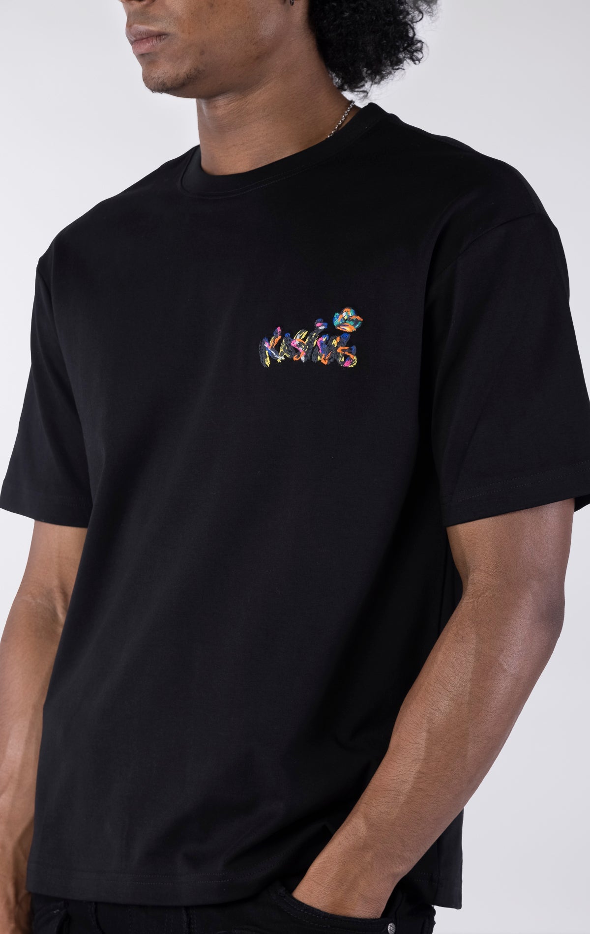 Black short-sleeve t-shirt showing the back, featuring a large, colorful, graffiti-style illustration of a cartoon character in a backwards cap and crown. The text "Bubu" and other tags surround the central image.