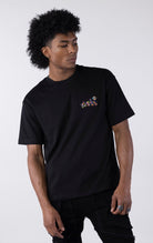 Black short-sleeve t-shirt showing the back, featuring a large, colorful, graffiti-style illustration of a cartoon character in a backwards cap and crown. The text "Bubu" and other tags surround the central image.