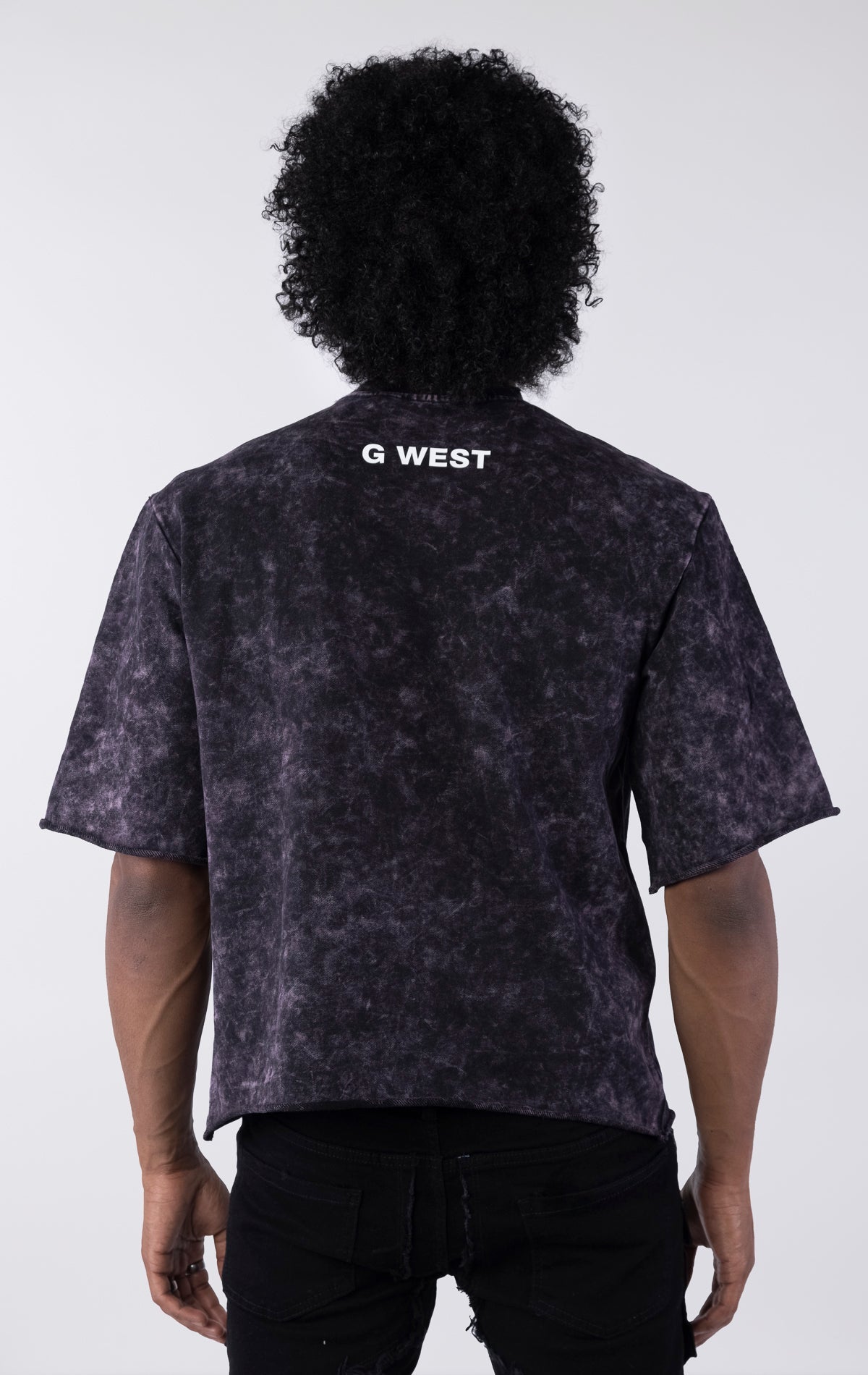 Person wearing a black tie-dye t-shirt with 'G West' branding on the back against a white background