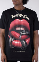 Person wearing a black t-shirt with a graphic design of red lips and a snake, text 'Trust No One', on a white background.