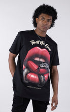 Person wearing a black t-shirt with a graphic design of red lips and a snake, text 'Trust No One' on a white background.