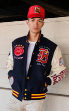 Blue, red and white jacket with leather sleeves, striped ribbed collar, cuffs, and waistband, along with chenille patches and embroidered designs and a snap button front closure