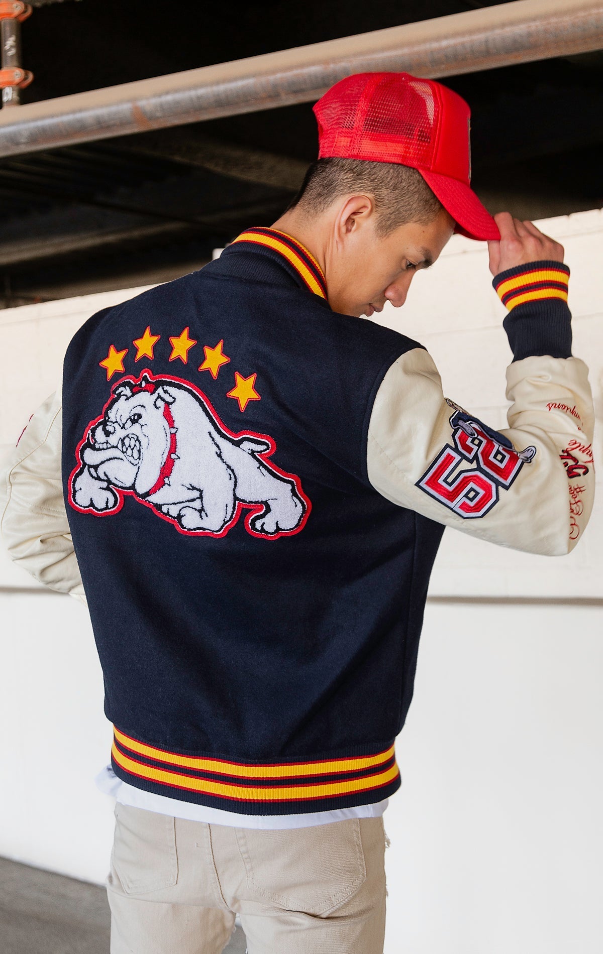 Blue, red and white jacket with leather sleeves, striped ribbed collar, cuffs, and waistband, along with chenille patches and embroidered designs and a snap button front closure