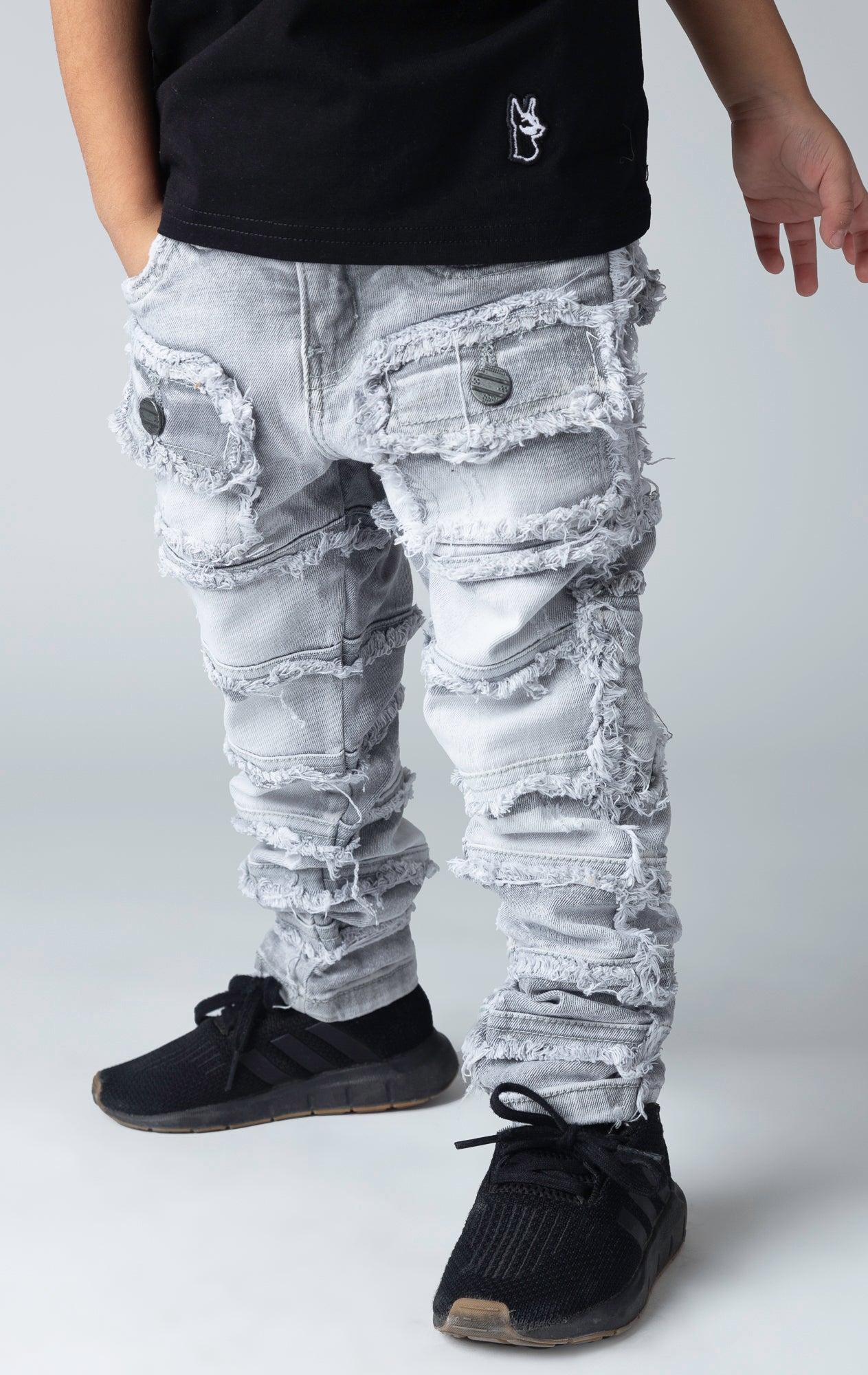 Stretch stacked denim pants for kids, distressed and paneled with a raw finishing 
