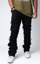 Edgy flare jeans feature a unique heavy wash, rip and repair design, and patches and abrasions throughout.