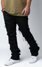 Edgy flare jeans feature a unique heavy wash, rip and repair design, and patches and abrasions throughout.