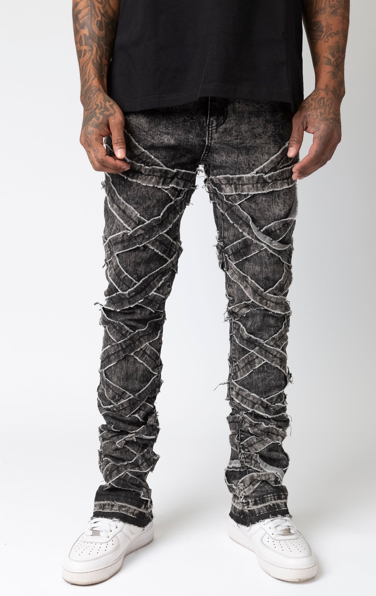 Black wash Distressed stacked jeans with a cut and sew panel construction, frayed detailing, and stretch fabric.
