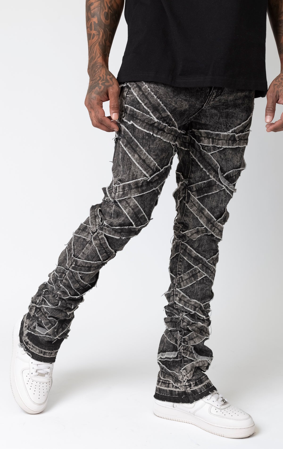 Black wash Distressed stacked jeans with a cut and sew panel construction, frayed detailing, and stretch fabric.