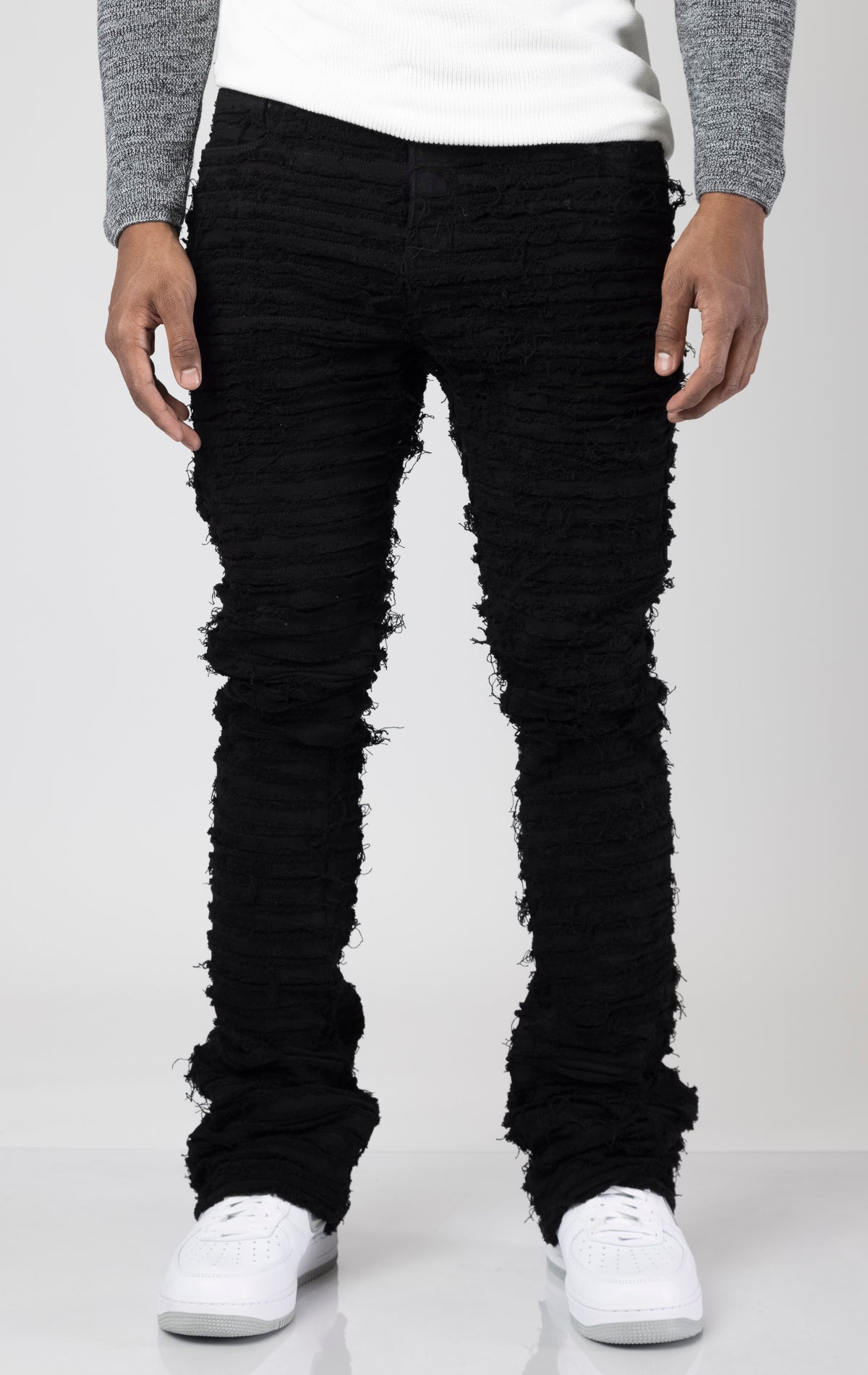 Black Men's mid-rise, non-stretch jeans in a dark wash with an extreme frayed logo design on the inseam. The jeans feature a stacked leg design, five pockets, belt loops, and a zipper fly with a top button closure. Made from 100% cotton.  