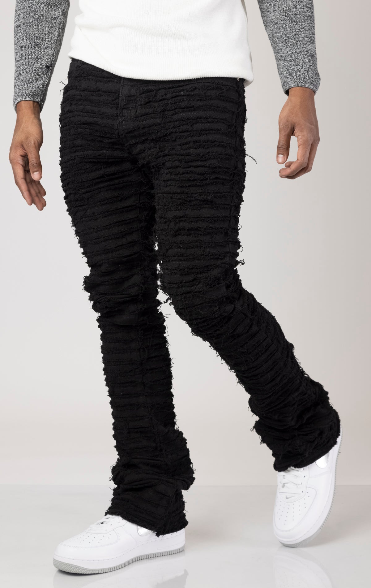 Black Men's mid-rise, non-stretch jeans in a dark wash with an extreme frayed logo design on the inseam. The jeans feature a stacked leg design, five pockets, belt loops, and a zipper fly with a top button closure. Made from 100% cotton.  