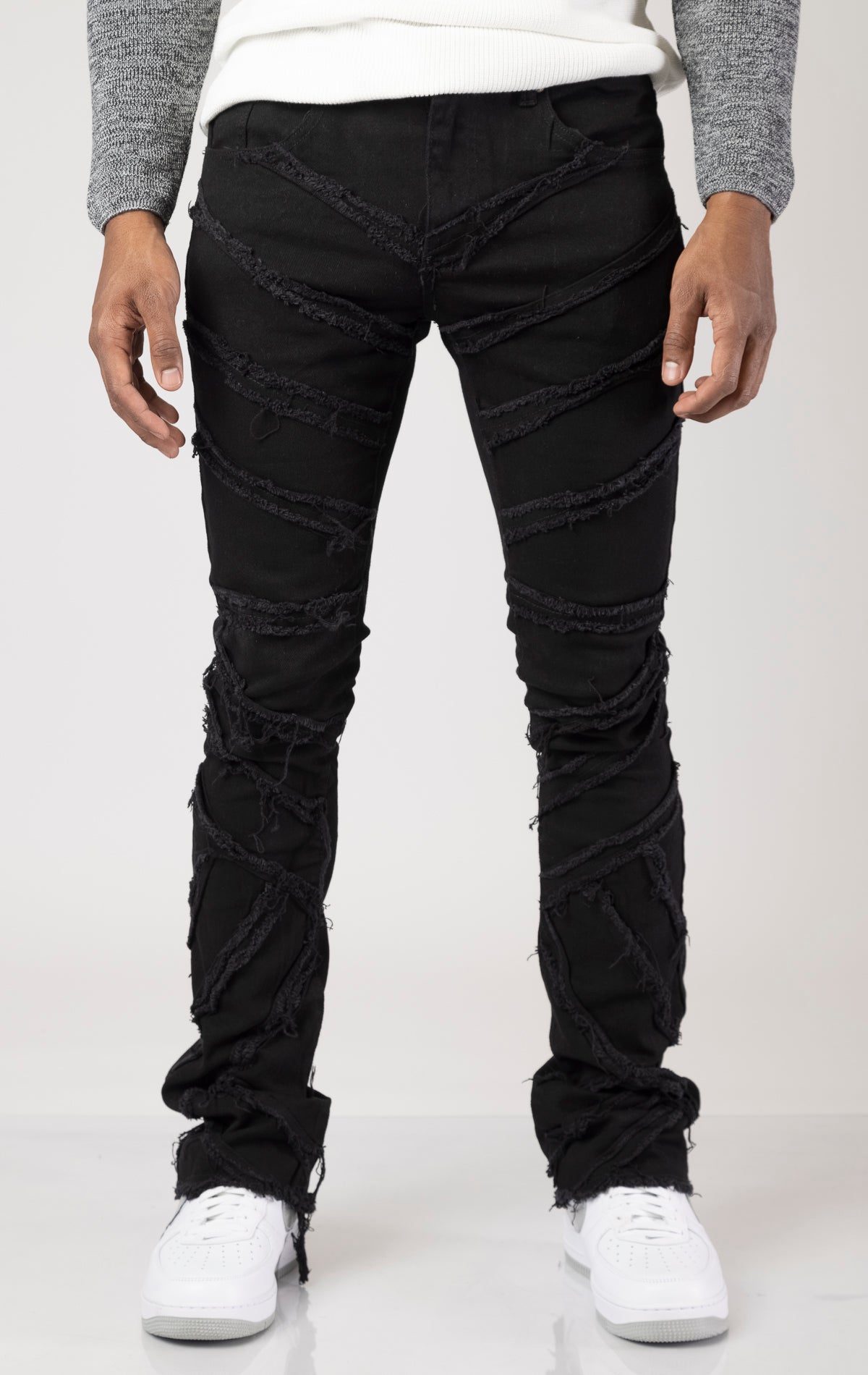 Men's mid-rise, stretchy jeans in a dark wash with a stacked leg design. The jeans feature a purple lace screen print throughout the legs, five pockets, belt loops, and a zipper fly with a top button closure.