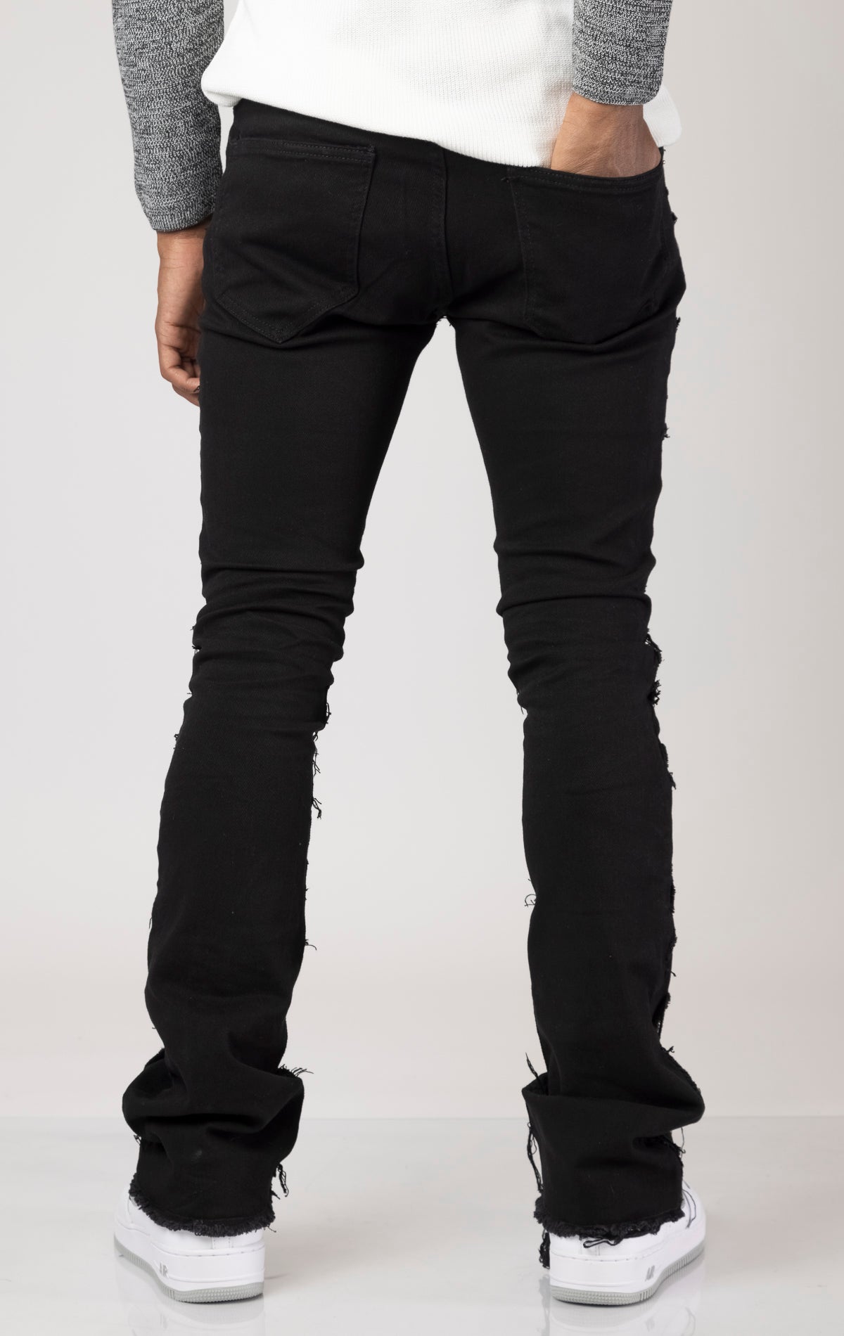 Men's mid-rise, stretchy jeans in a dark wash with a stacked leg design. The jeans feature a purple lace screen print throughout the legs, five pockets, belt loops, and a zipper fly with a top button closure.