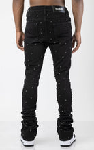 Men's black, tapered-fit jeans with a luxurious cotton-blend fabric (98% cotton, 2% elastane) and custom hardware. The jeans feature subtle laser distressing throughout, delicate diamond embellishments, and a five-pocket design. They stack comfortably abo