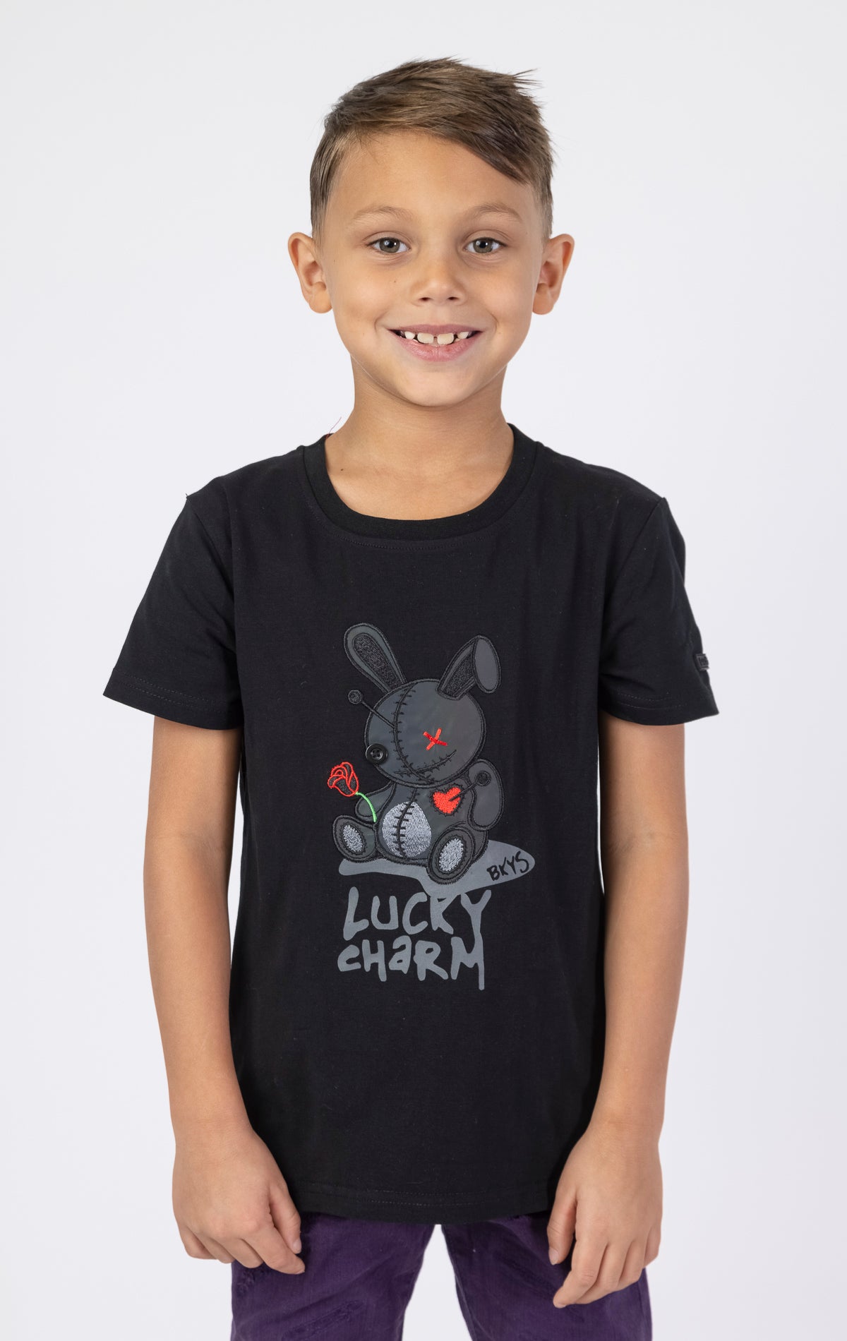 Black Keys Kids Lucky Charm Tee with a black reflective patch. Made from a soft blend of 95% cotton and 5% spandex. Features a crewneck style and a playful lucky charm graphic