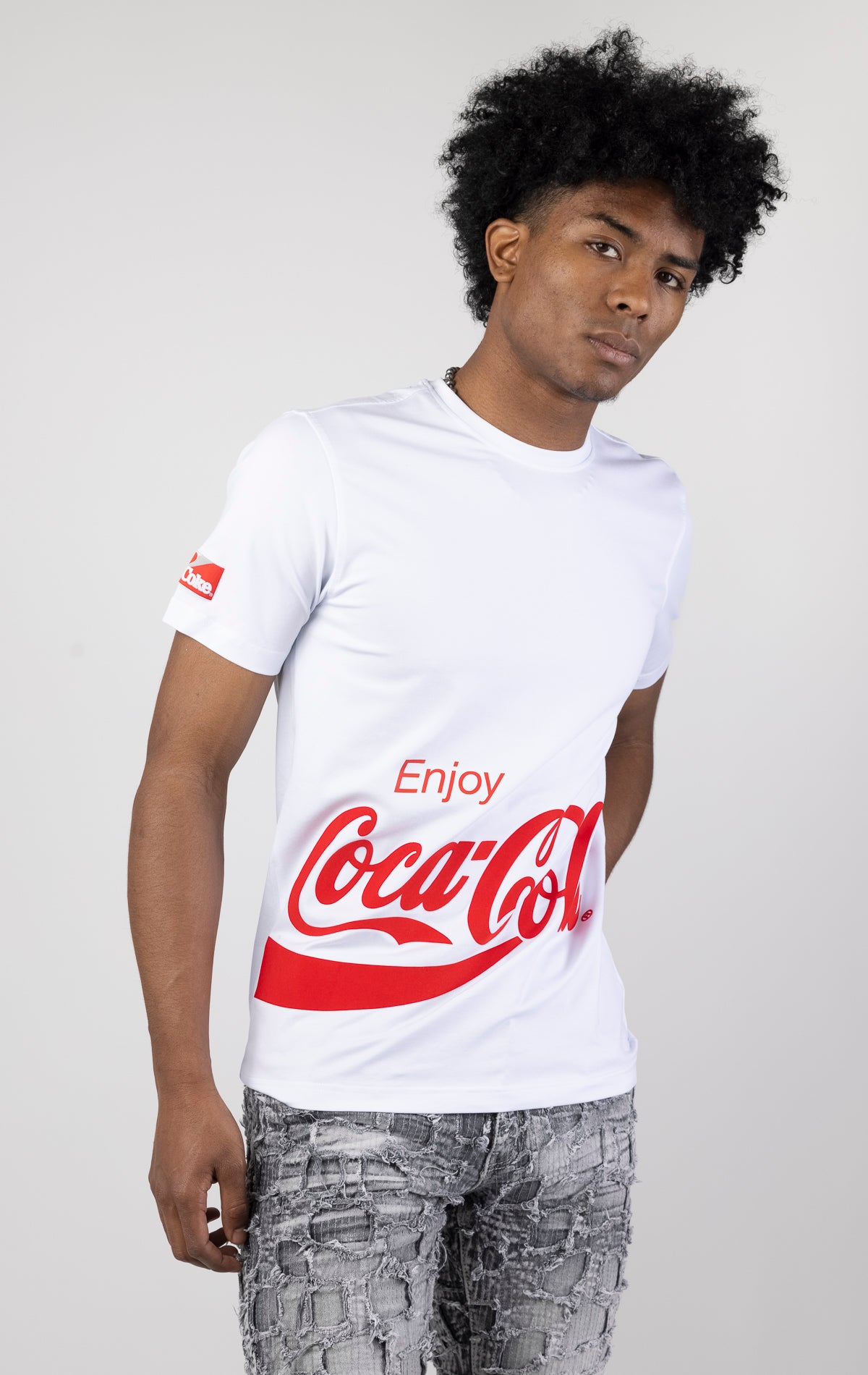 Men's short-sleeve crew neck t-shirt in a variety of colors. The shirt features a Coca-Cola logo graphic on the front. The graphic is heat-sealed and the tee is made from a blend of 94% cotton and 6% spandex.