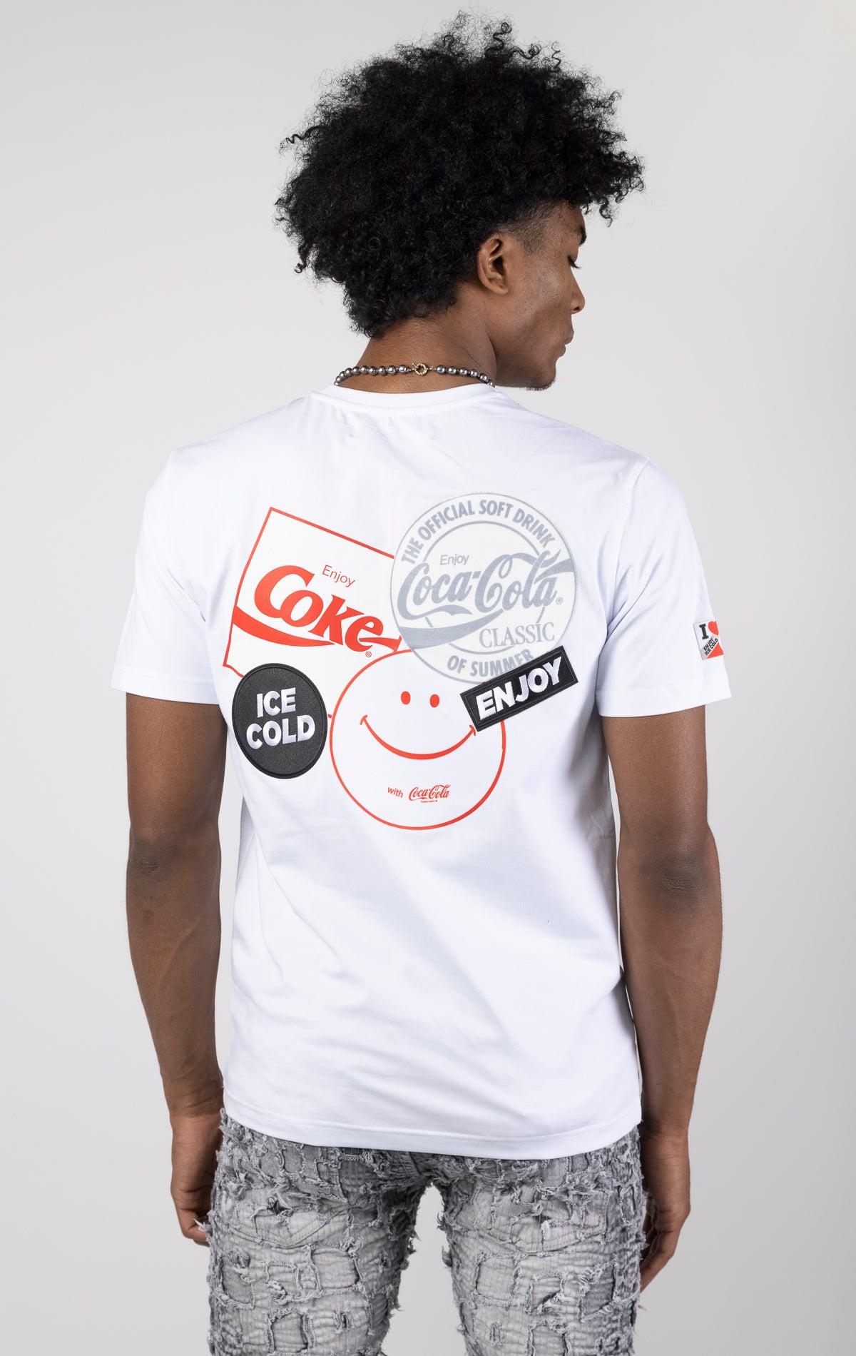 Men's short-sleeve crew neck t-shirt in a variety of colors. The shirt features a Coca-Cola logo graphic on the front. The graphic is heat-sealed and the tee is made from a blend of 94% cotton and 6% spandex.