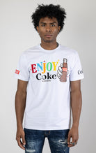 Men's white short-sleeve crew neck t-shirt in a variety of colors. The shirt features a Coca-Cola logo graphic on the front. The graphic is heat-sealed and the tee is made from a blend of 94% cotton and 6% spandex.