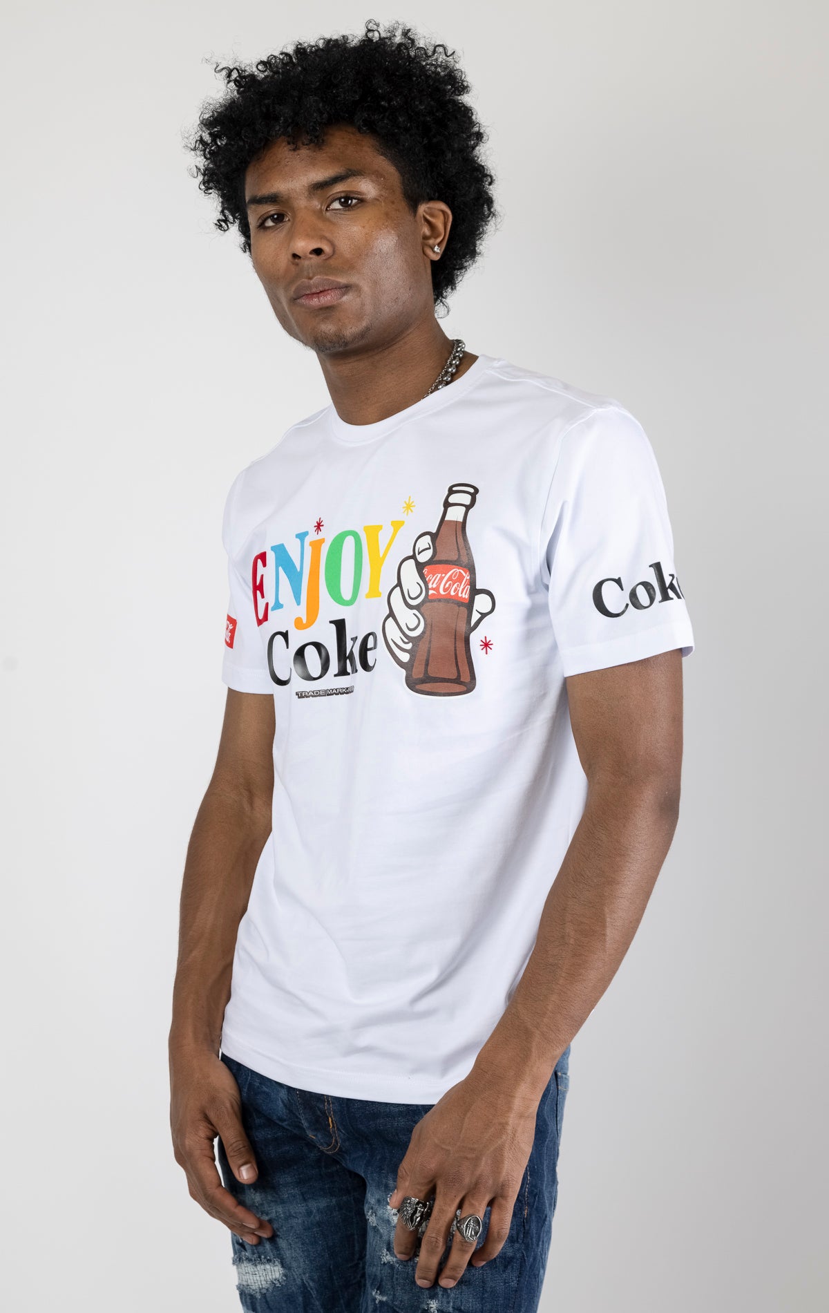 Men's white short-sleeve crew neck t-shirt in a variety of colors. The shirt features a Coca-Cola logo graphic on the front. The graphic is heat-sealed and the tee is made from a blend of 94% cotton and 6% spandex.