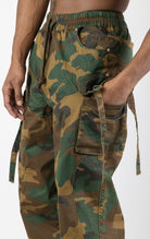 Men's baggy cargo pants in camo. The pants feature a wide, relaxed fit from the waist down, paneled construction, spacious cargo pockets with loop closures and functional tightening straps, and custom hardware. Made from a blend of 98% cotton and 2% spandex.