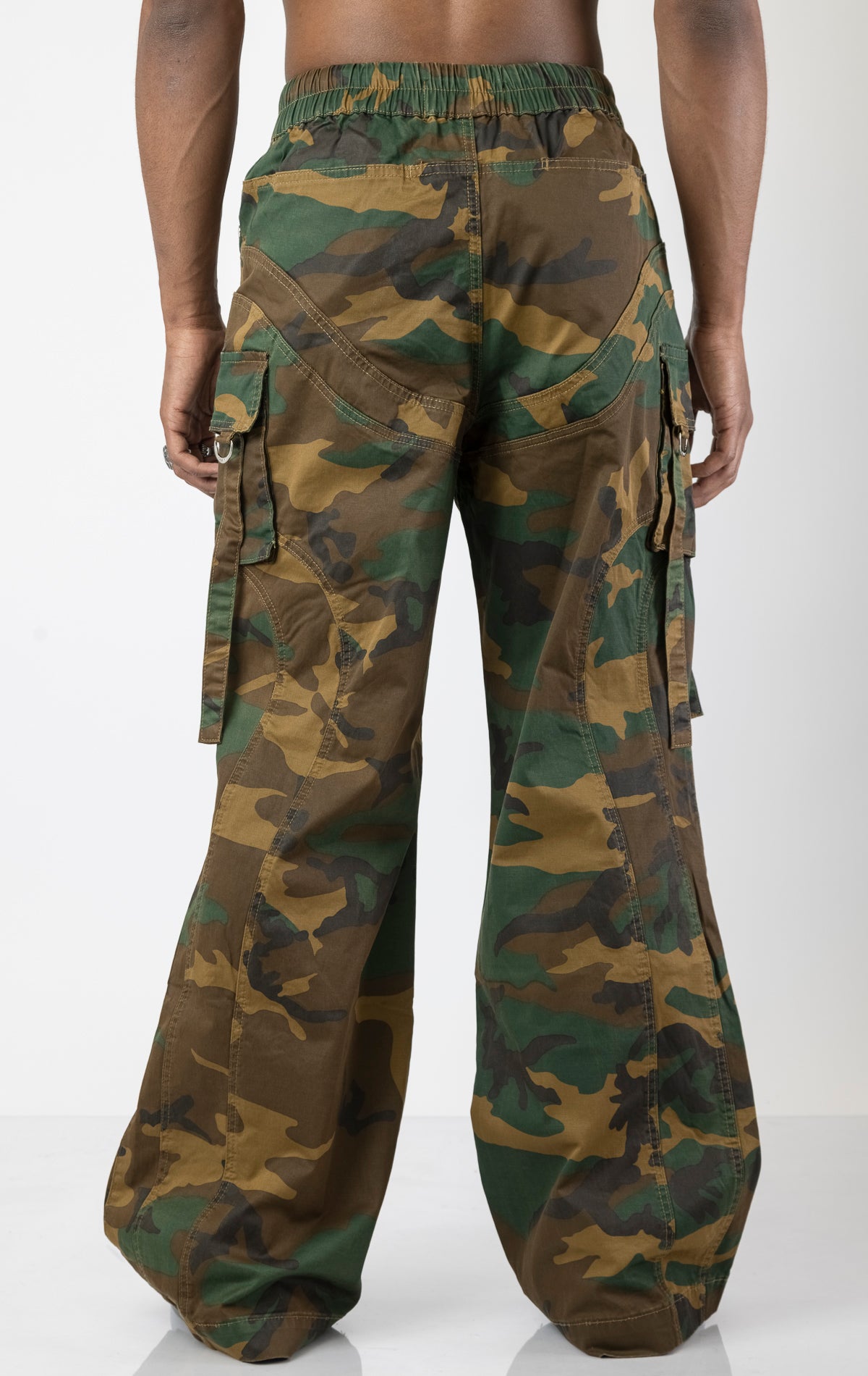 Men's baggy cargo pants in camo. The pants feature a wide, relaxed fit from the waist down, paneled construction, spacious cargo pockets with loop closures and functional tightening straps, and custom hardware. Made from a blend of 98% cotton and 2% spandex.