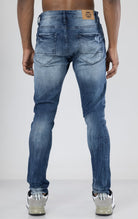 Men's ripped and distressed denim pants in a variety of washes. The pants feature a regular rise, tapered fit from the knee down, open rips at the knees, unique distressing details, and are made from 98% cotton with 2% lycra for stretch