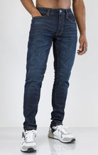 Men's Sean Slim Taper jeans in dark indigo. The jeans feature a regular rise waist, a comfortable fit from waist to thigh, a slim taper from knee to ankle, 3D baked wrinkles for texture, a raw denim look, and are made from a super stretch fabric blend (35