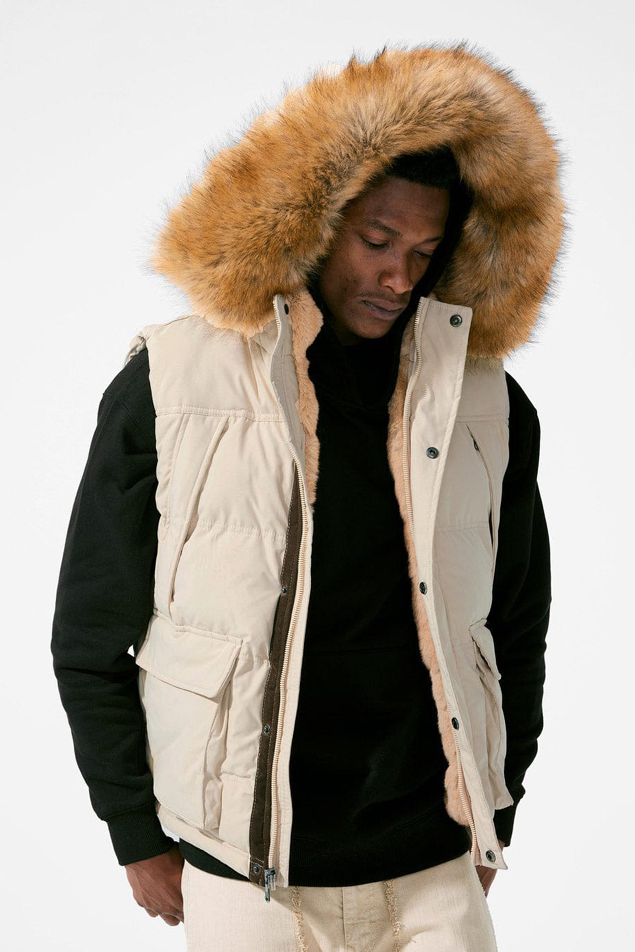 Khaki Faux fur-lined hooded jacket made of a water-resistant polyester shell featuring a removable hood with a removable faux fox fur trim. The hood and front of the jacket are lined with faux rabbit fur for superior warmth. The jacket has JC branded zippers throughout, dual pockets at the sides with button openings, and a full zipper front opening. Faux suede taping adorns the front zipper.