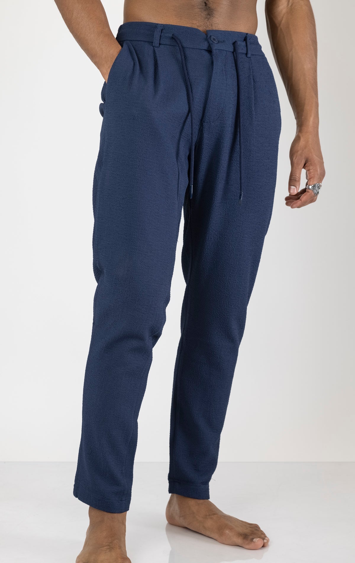 Men's front pleated waffle pants in navy. The pants are made from a textured waffle fabric (95% cotton, 5% elastane) and feature a relaxed fit, front pleats, and a comfortable elastic waistband.