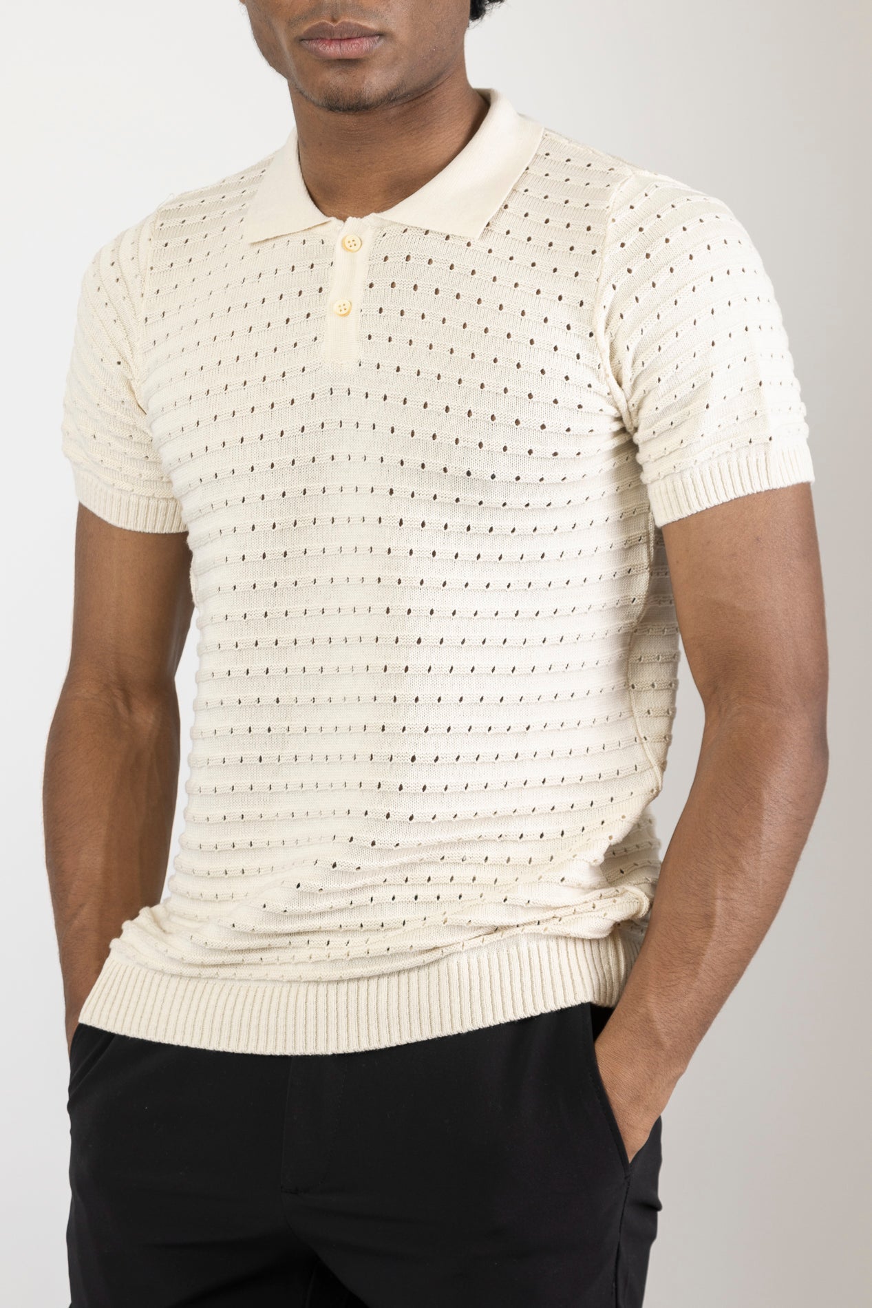 Men's eyelet short sleeve polo tee in Beige. The shirt is made from a soft and breathable fabric (50% viscose, 50% polyamide) and features a classic polo collar, short sleeves, and delicate eyelet detailing along the sleeves.