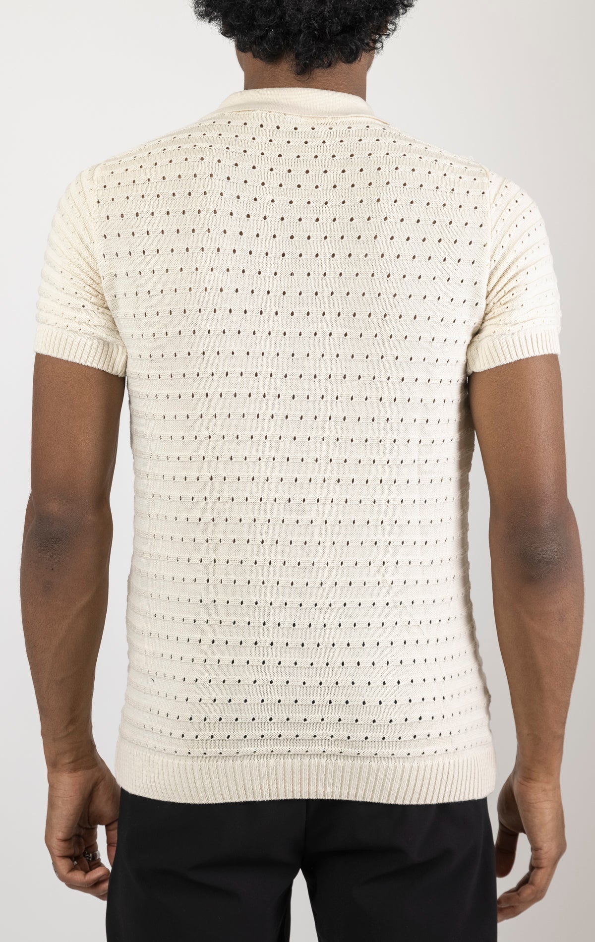 Men's eyelet short sleeve polo tee in Beige. The shirt is made from a soft and breathable fabric (50% viscose, 50% polyamide) and features a classic polo collar, short sleeves, and delicate eyelet detailing along the sleeves.