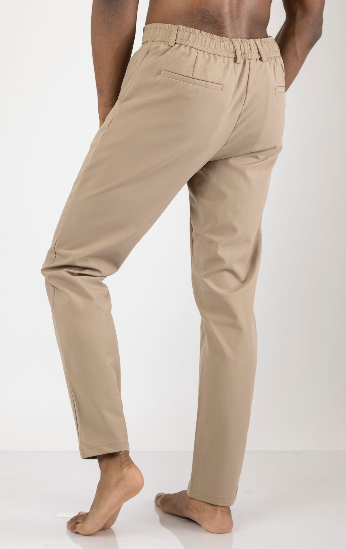 Men's wrinkle-free tapered travel pants in camel color. The pants are made from a blend of polyamide (88%) and elastane (12%) and feature a tapered fit, wrinkle-resistant fabric, and multiple pockets.