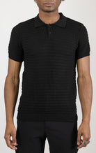 Men's eyelet short sleeve polo tee in Black . The shirt is made from a soft and breathable fabric (50% viscose, 50% polyamide) and features a classic polo collar, short sleeves, and delicate eyelet detailing along the sleeves.