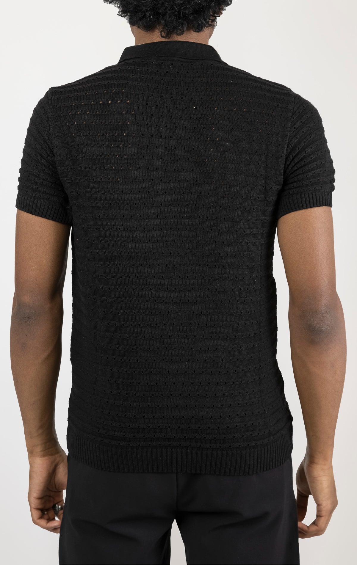 Men's eyelet short sleeve polo tee in Black . The shirt is made from a soft and breathable fabric (50% viscose, 50% polyamide) and features a classic polo collar, short sleeves, and delicate eyelet detailing along the sleeves.