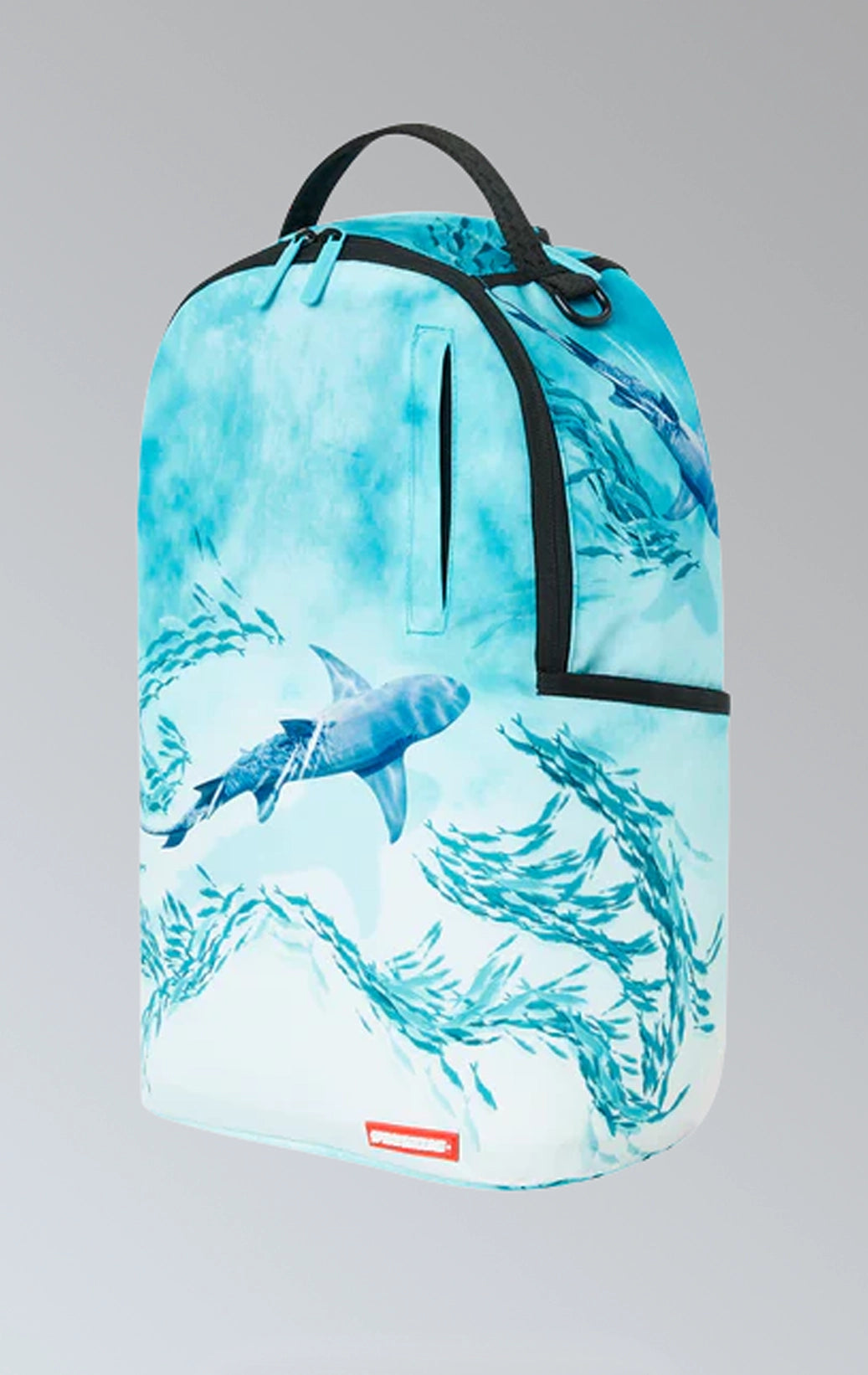 Sprayground backpack with shark graphic, gold zippers and metal hardware featuring multiple compartments and pockets, including a separate velour laptop compartment and a velour sunglass compartment. It has ergonomic mesh back padding, adjustable straps, and a slide-through back sleeve for attaching to carry-on luggage.  The backpack is made from durable 900D polyester fabric.