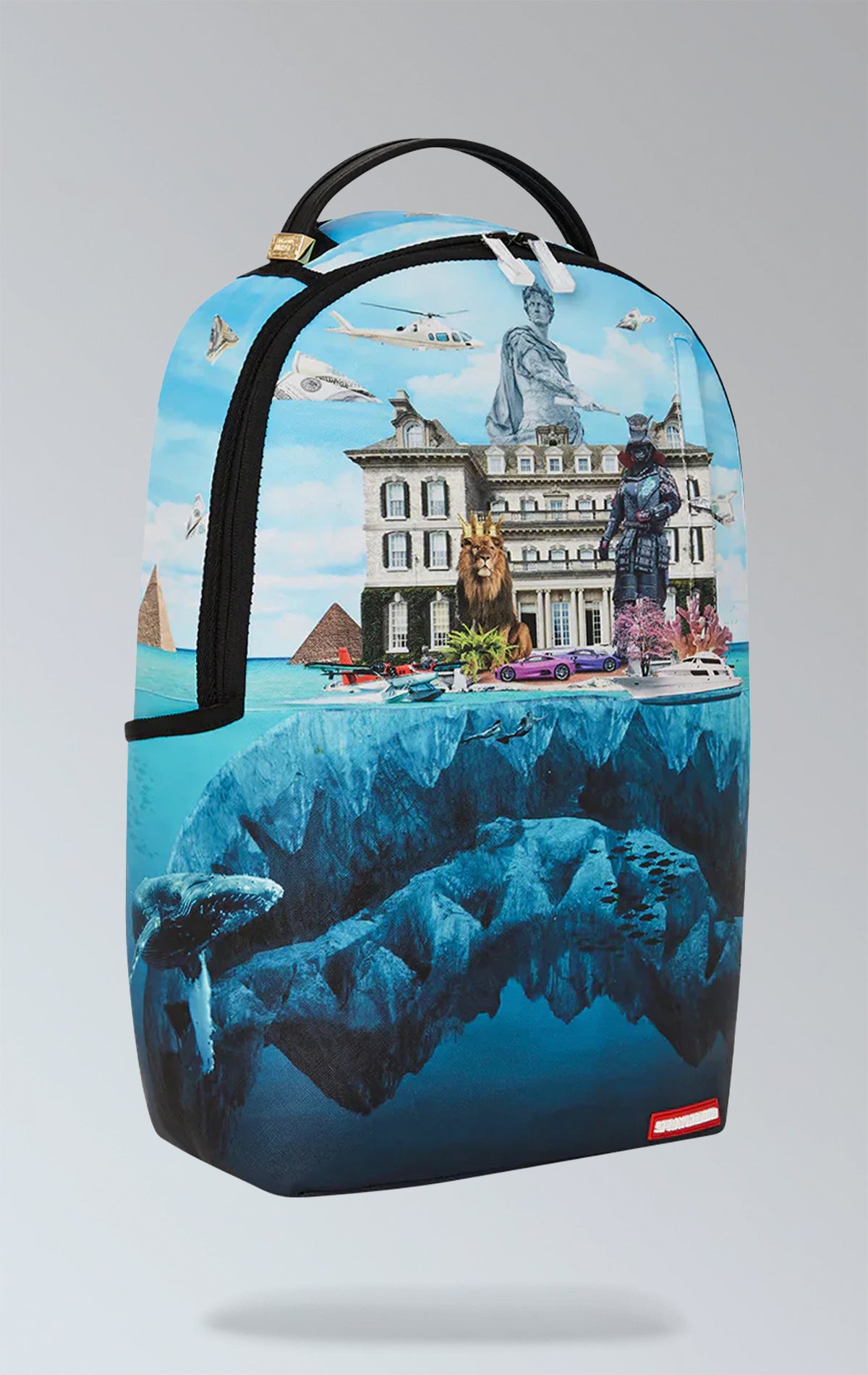 Eye-catching blue Sprayground backpack featuring artwork of a luxury mansion atop a shark, with separate laptop & sunglasses compartments, padded back, and luggage sleeve.