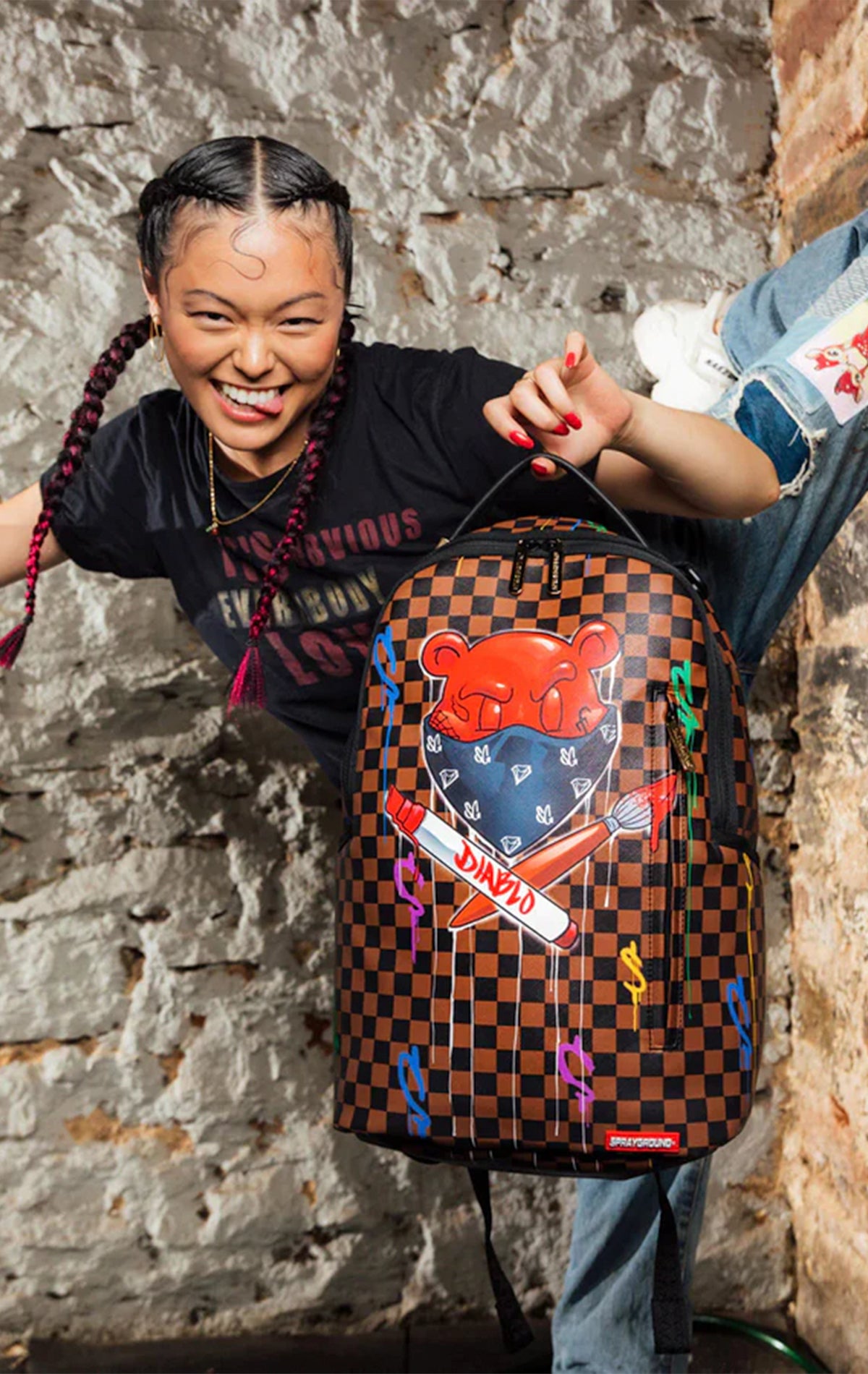 Sprayground fiery checkerboard backpack with mischievous bear mascot, perfect for rebellious spirits!