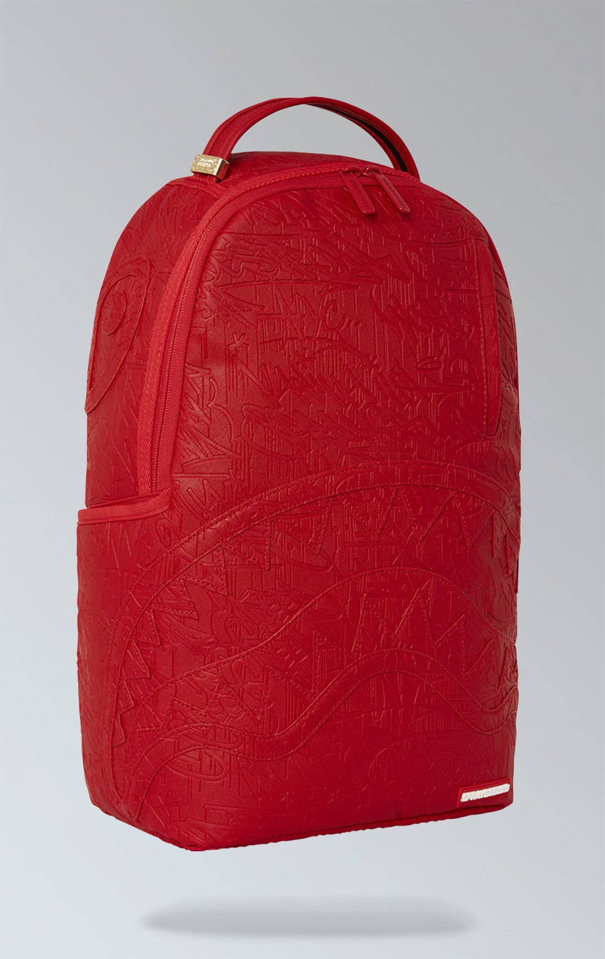 Red Sprayground backpack with an eye-catching scribble design. Features multiple compartments including a separate velour laptop compartment, side pockets, and a hidden zippered pocket. Equipped with ergonomic mesh back padding, adjustable straps, and a sliding back sleeve for attaching to carry-on luggage. Made from durable vegan leather.