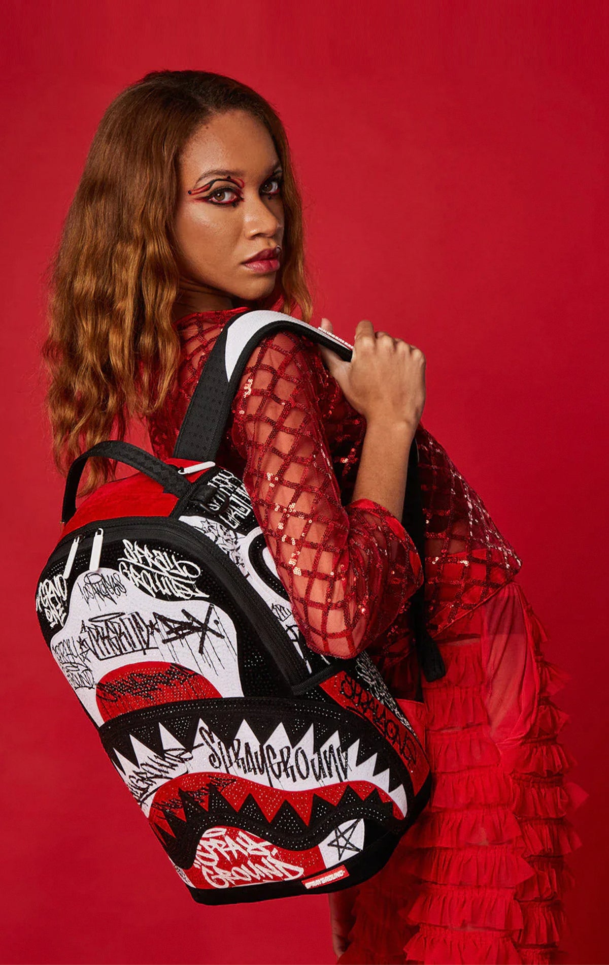Fiery red Sprayground Vandal Trinity backpack with three flip faces, separate laptop & sunglasses compartments, and luggage sleeve.