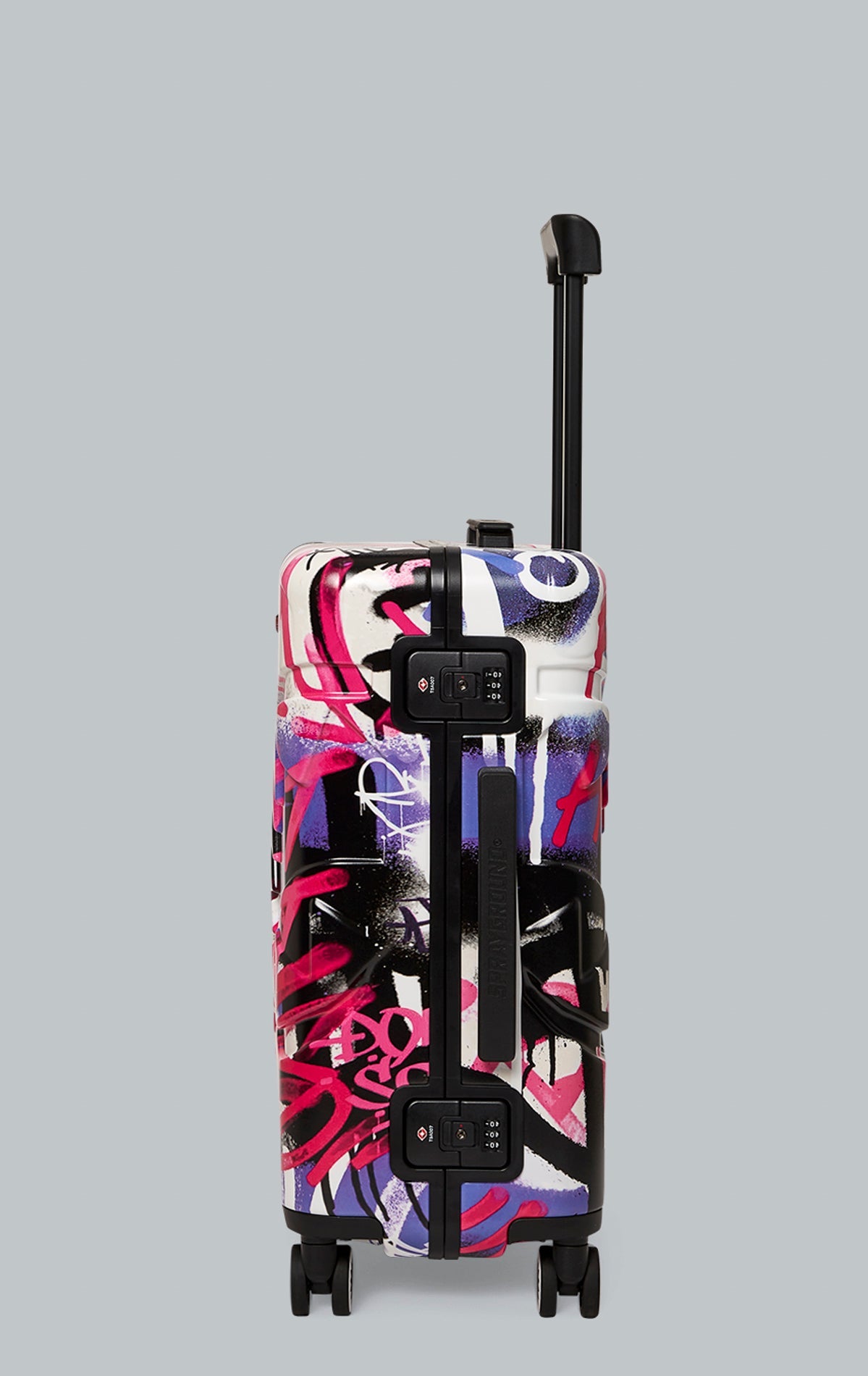 Sprayground Vandal Couture Carry On luggage in black with a patented shark sculpture. The carry-on features a hard-shell exterior, TSA security locks, a telescoping handle, four dual-spinning wheels, and a zipperless aluminum alloy frame. The interior fea