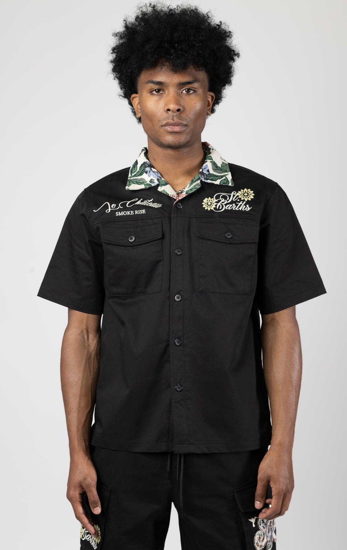 Men's short-sleeve button-up shirt in either black. The shirt features a tapestry design on the back with complementary embroidery details. Made from 100% cotton. The fit is regular.