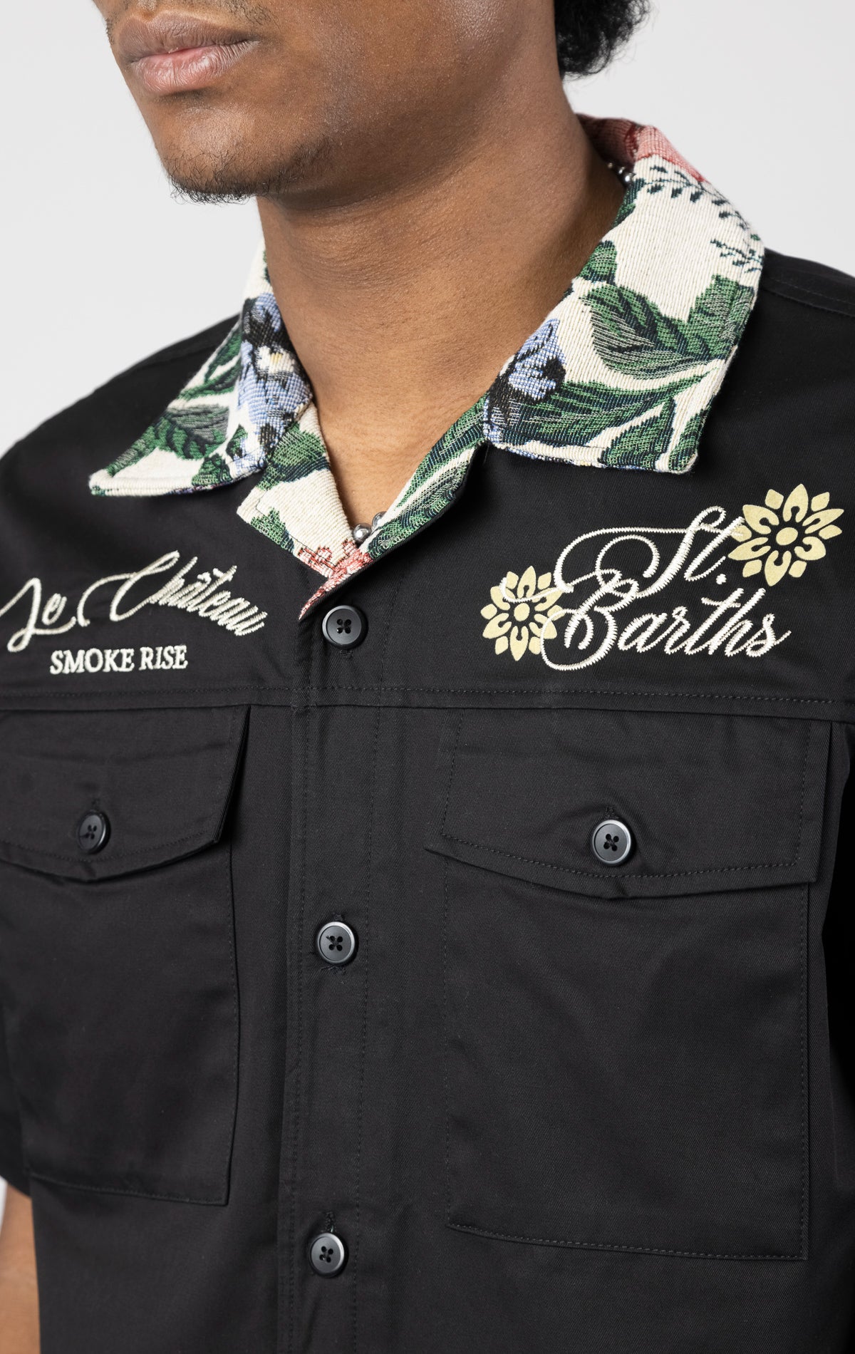 Men's short-sleeve button-up shirt in either black. The shirt features a tapestry design on the back with complementary embroidery details. Made from 100% cotton. The fit is regular.