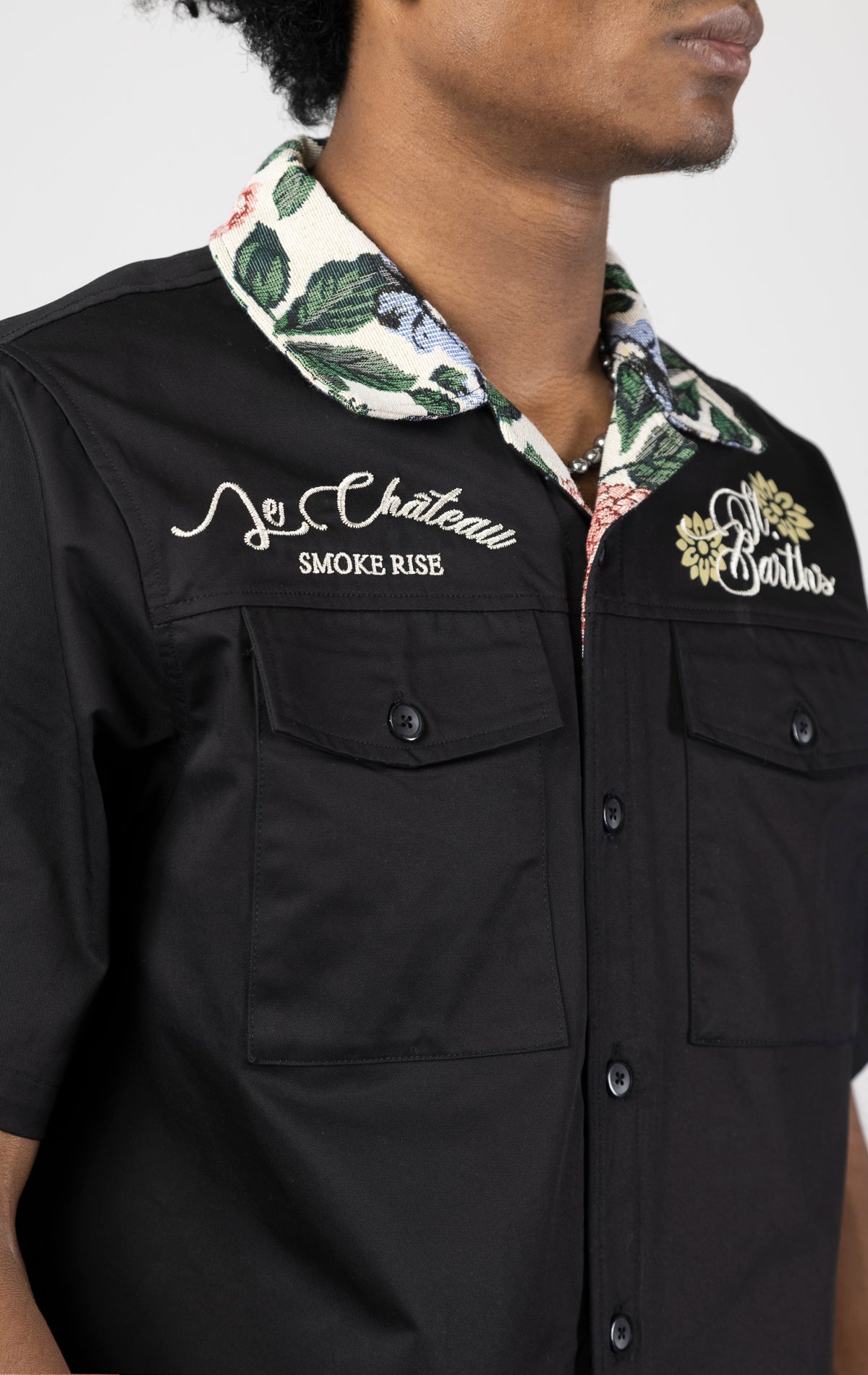 Men's short-sleeve button-up shirt in either black. The shirt features a tapestry design on the back with complementary embroidery details. Made from 100% cotton. The fit is regular.