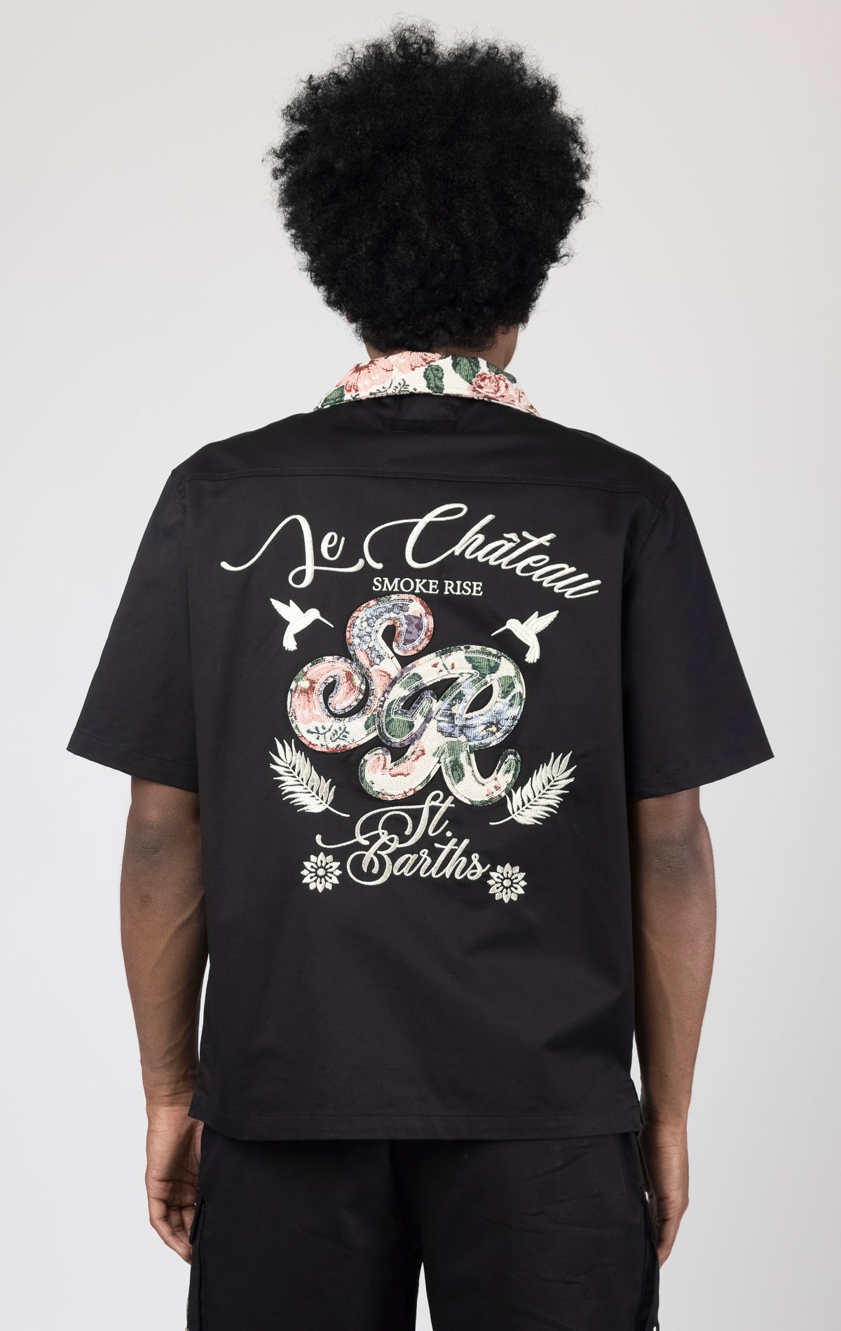 Men's short-sleeve button-up shirt in either black. The shirt features a tapestry design on the back with complementary embroidery details. Made from 100% cotton. The fit is regular.