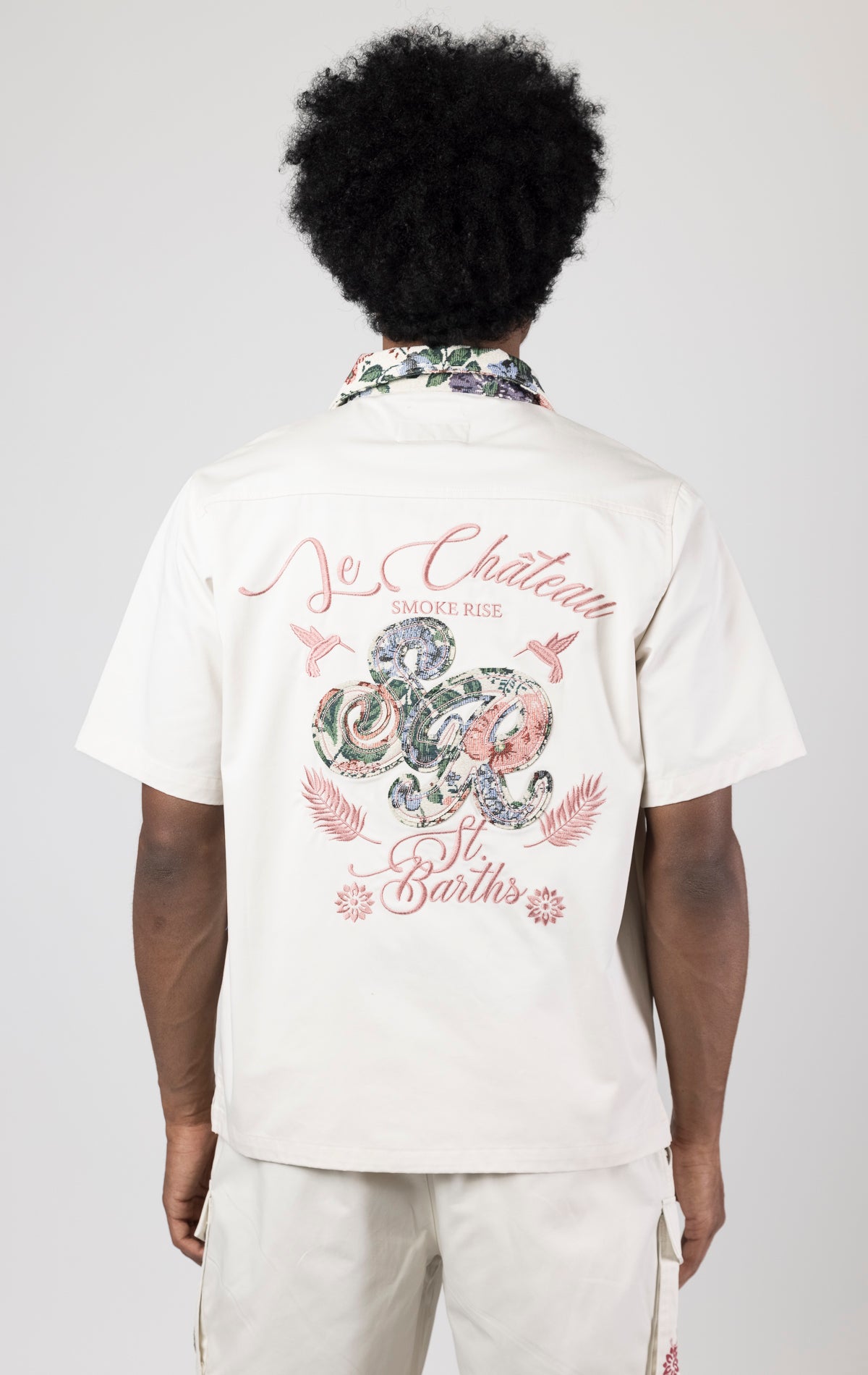 Men's short-sleeve button-up shirt in either chalk. The shirt features a tapestry design on the back with complementary embroidery details. Made from 100% cotton. The fit is regular.